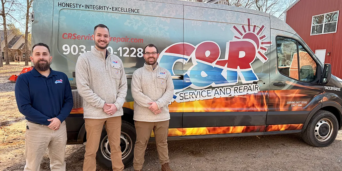Team of HVAC technicians standing in front of service vehicles