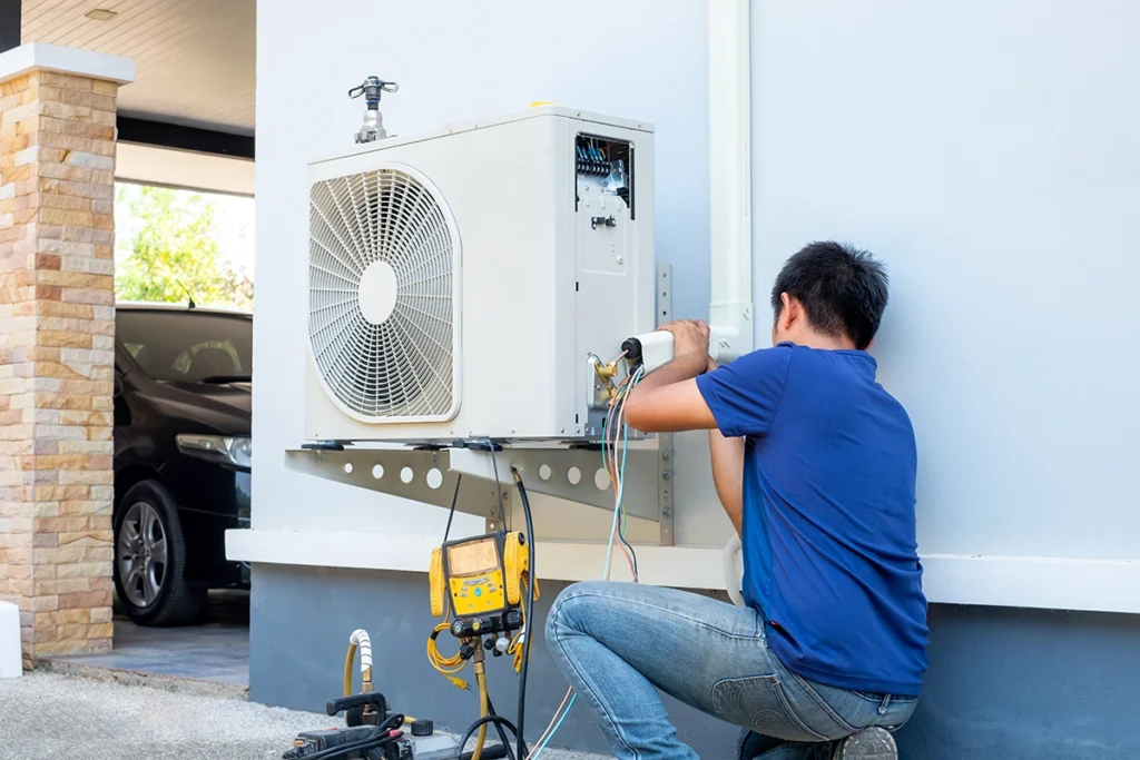technician working to fix a heat pump by diagnosing the outdoor unit components
