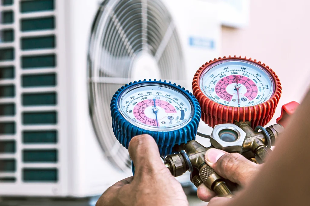 Technician checking HVAC gauges during service on an air conditioning system that uses R32 refrigerant