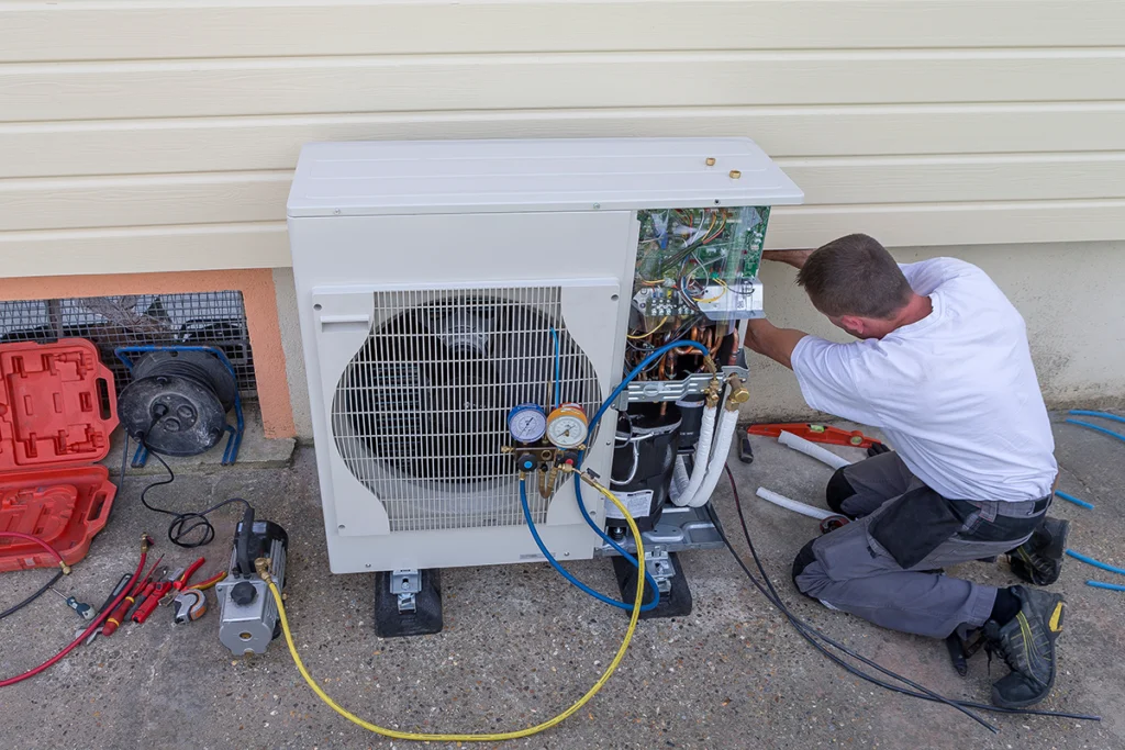 HVAC technician servicing an outdoor heat pump Brownsboro homeowners use for year-round heating and cooling.