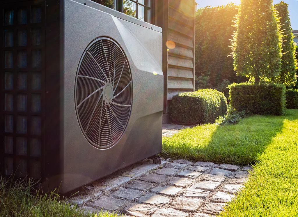 Outdoor heat pump unit for heat pump Ben Wheeler service beside a home in sunny weather