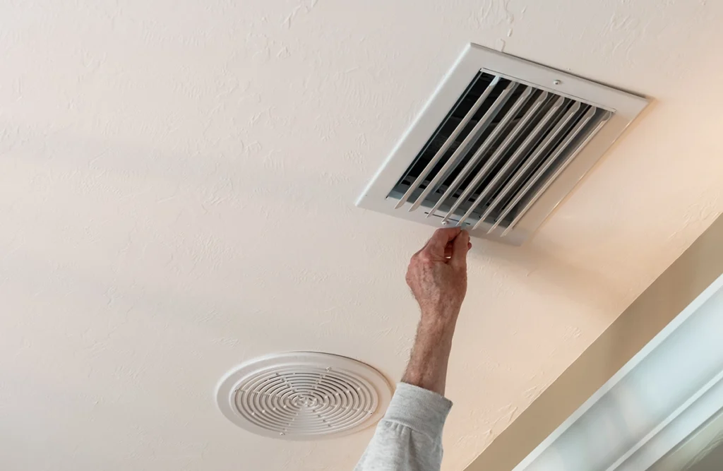Air handler producing a musty smell from the evaporator coil in Whitehouse, with a homeowner checking an HVAC ceiling vent.