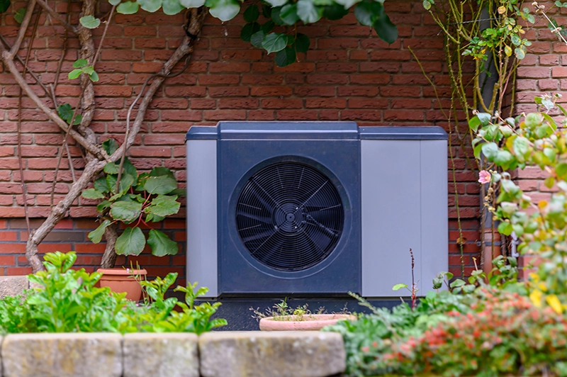 Best heat pump Emerald Bay outdoor unit installed beside a brick home with surrounding landscaping.