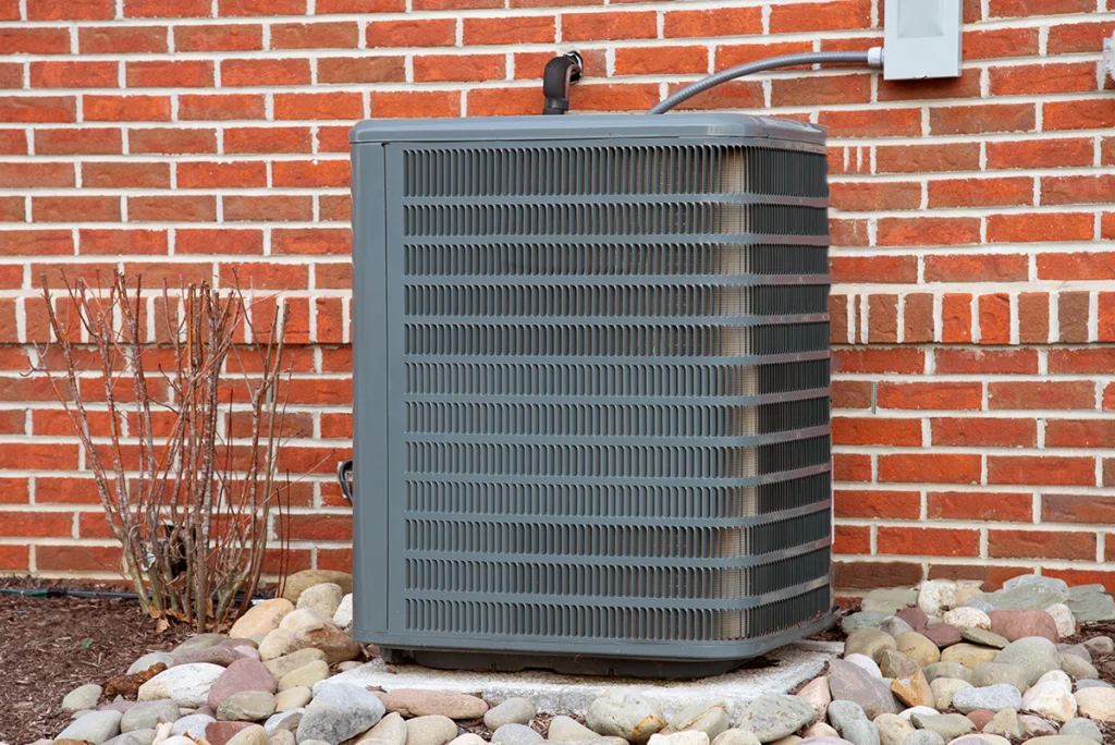 Central AC setup with outdoor condenser unit installed beside a brick home.